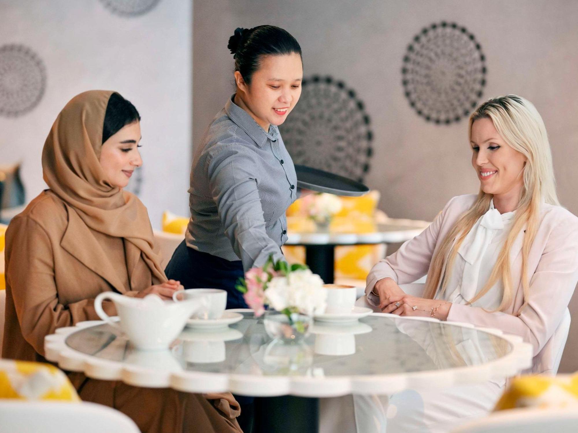 Moevenpick Hotel & Apartments Ghala Maskat Exteriér fotografie A waitress serving customers
